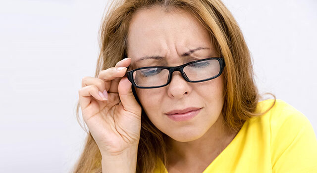person wearing yellow shirt squinting into glasses.jpg